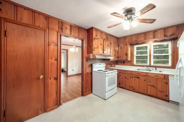 a kitchen with stainless steel appliances granite countertop a refrigerator a sink dishwasher a stove with white cabinets and wooden floor