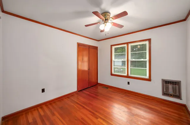 an empty room with wooden floor chandelier and windows