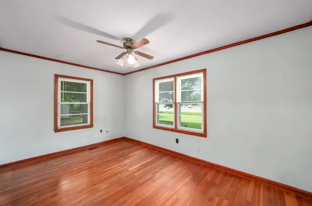 a view of an empty room with a window and wooden floor