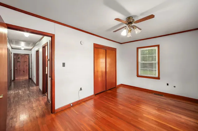 a view of an empty room with window and wooden floor