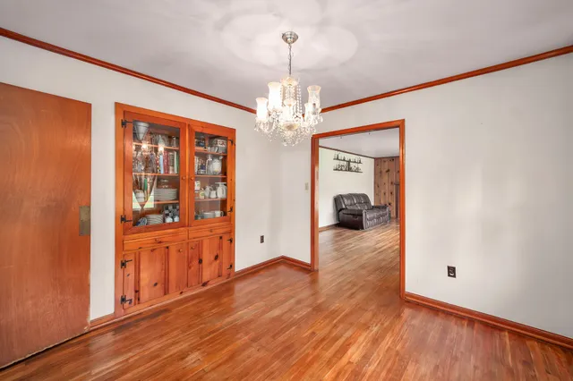 a hallway with wooden floor chandelier and livingroom