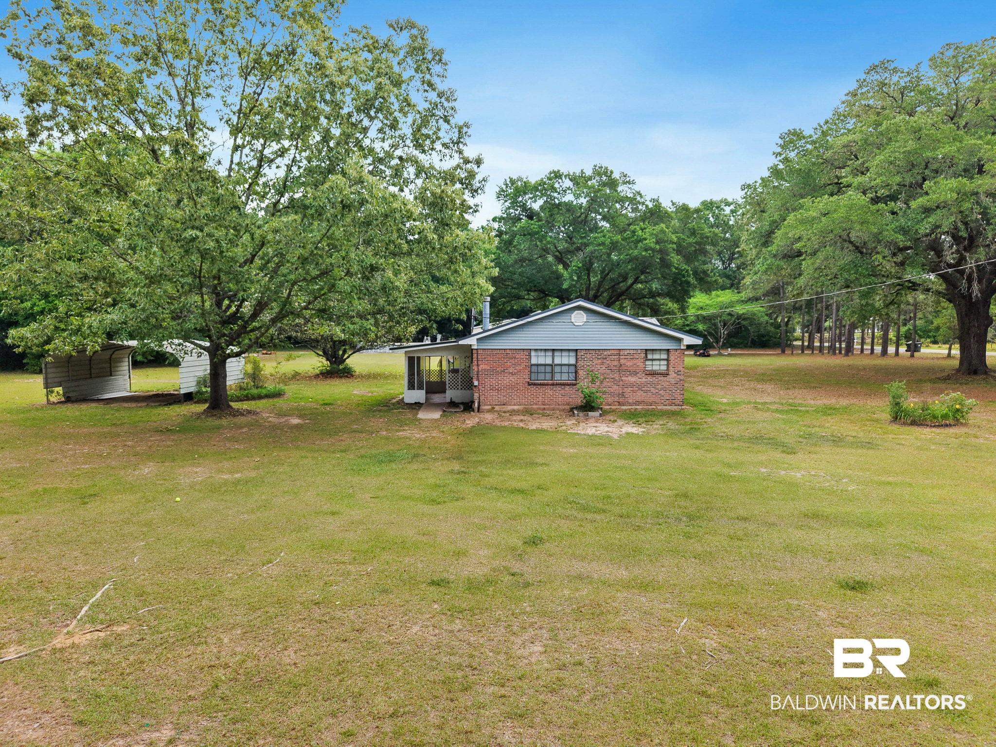 13653 Roberts Road Loxley, AL 36551 - Photo 27 of 33 Brick exterior home with a screened porch, large mature trees, expansive green lawn, and an outbuilding