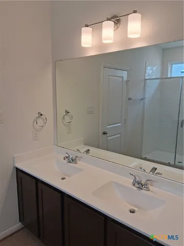 a bathroom with a sink double vanity granite tub shower and a mirror