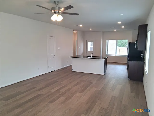 a view of a kitchen with wooden floor and a ceiling fan