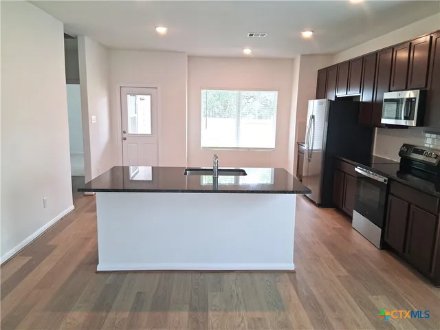 a living room with stainless steel appliances kitchen island granite countertop a stove a refrigerator a sink and a refrigerator