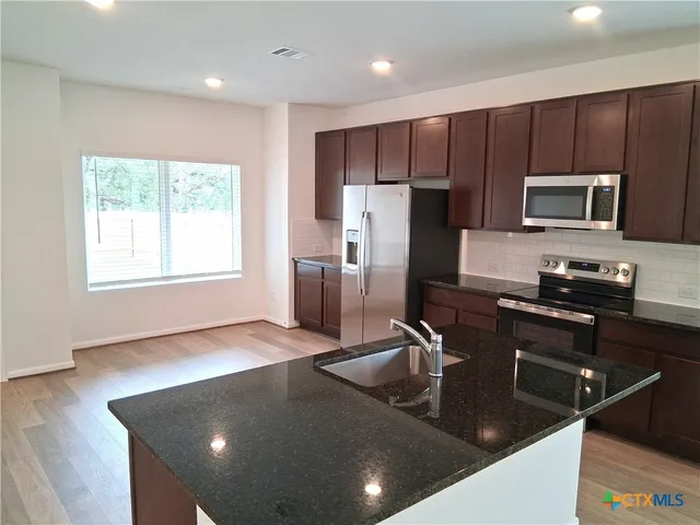 a kitchen with kitchen island a counter space a sink appliances and cabinets