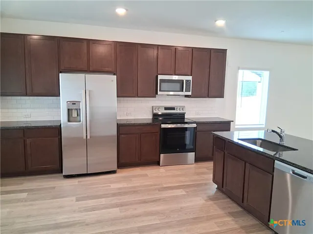 a kitchen with stainless steel appliances granite countertop a sink stove and refrigerator