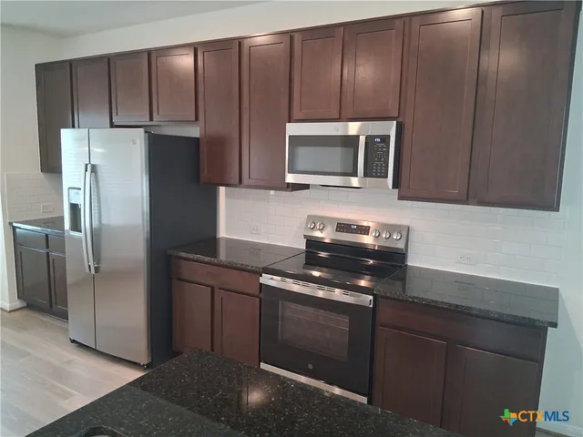 a kitchen with wooden cabinets and stainless steel appliances