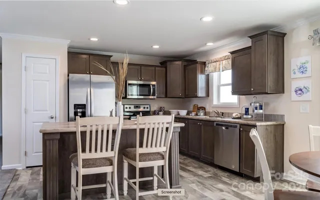 a kitchen with stainless steel appliances granite countertop a stove a sink a microwave a refrigerator and cabinets