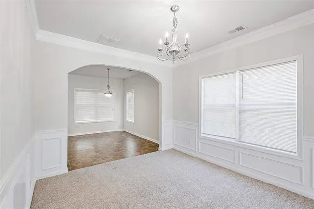 an empty room with chandelier fan and windows