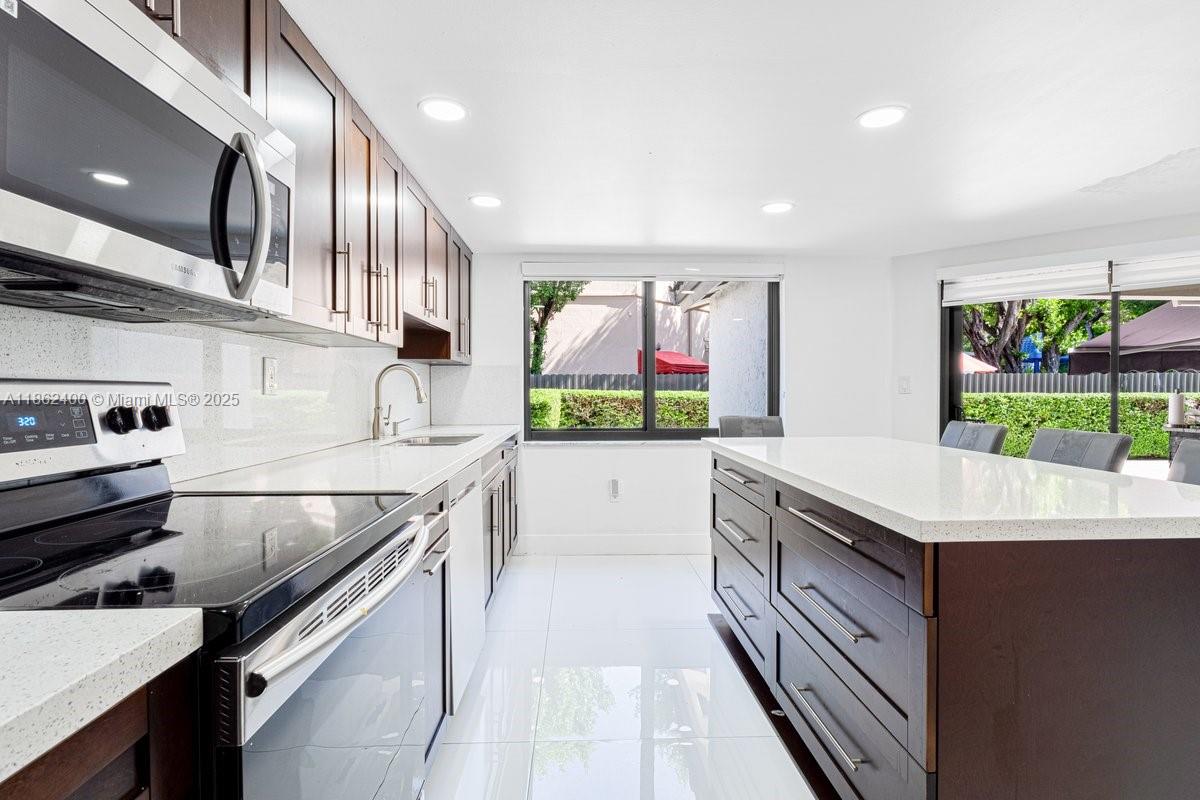 9035 Southwest 156th Court Miami, FL 33196 - Photo 11 of 33 a kitchen with stainless steel appliances granite countertop a sink and stove
