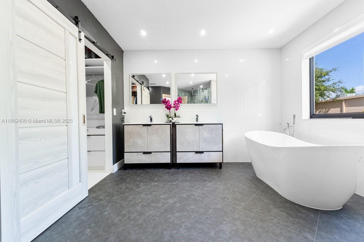 9035 Southwest 156th Court Miami, FL 33196 - Photo 16 of 33 a bathroom with a white tub shower and hallway