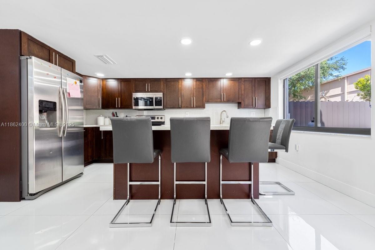 9035 Southwest 156th Court Miami, FL 33196 - Photo 10 of 33 a view of kitchen with stainless steel appliances granite countertop dining table chairs sink and cabinets