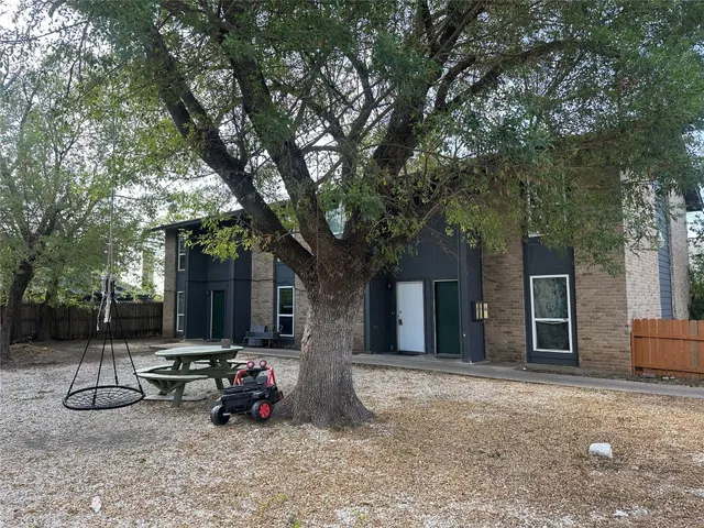 a view of a patio with table and chairs and a large tree