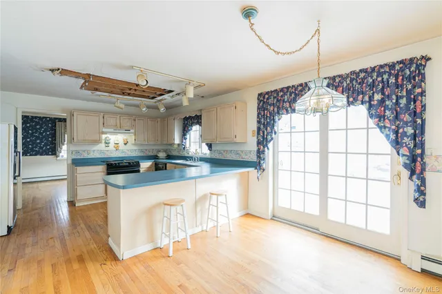 a view of a kitchen with kitchen island a counter top space a sink stainless steel appliances and cabinets