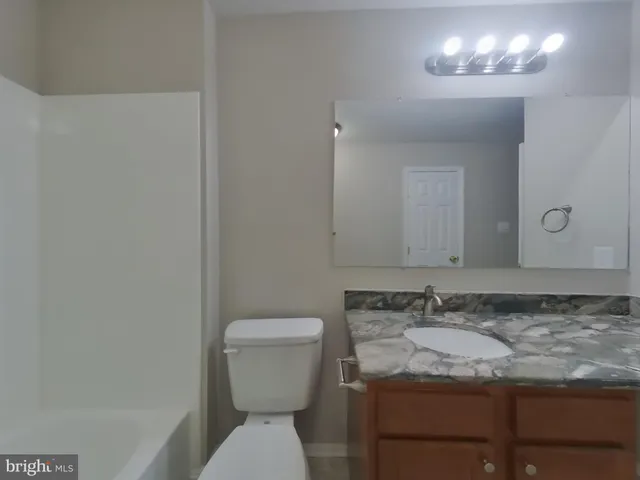 a bathroom with a granite countertop sink and a toilet