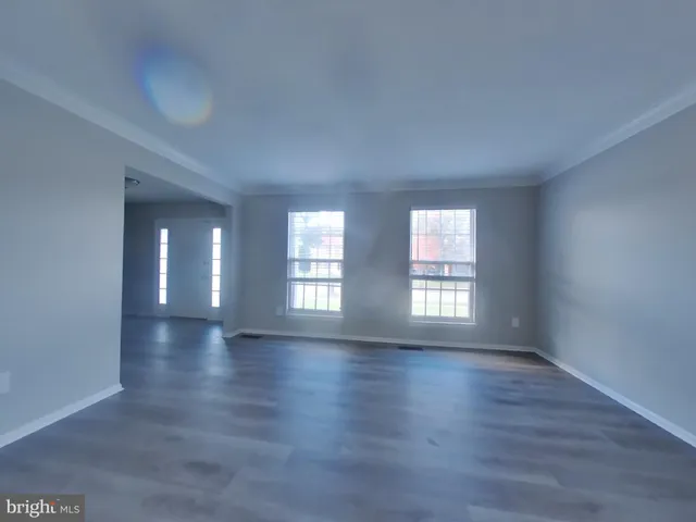 a view of an empty room with wooden floor and window