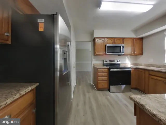 a kitchen with stainless steel appliances granite countertop a refrigerator and a stove top oven