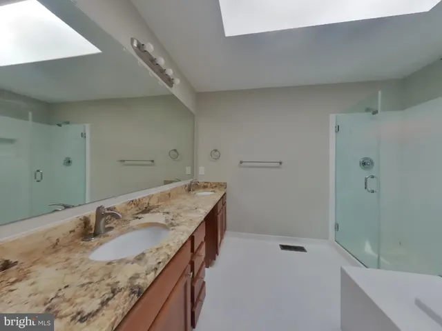 a bathroom with a granite countertop sink a mirror and shower