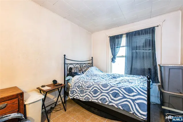 a bedroom with a bed and a chair with the wooden floor