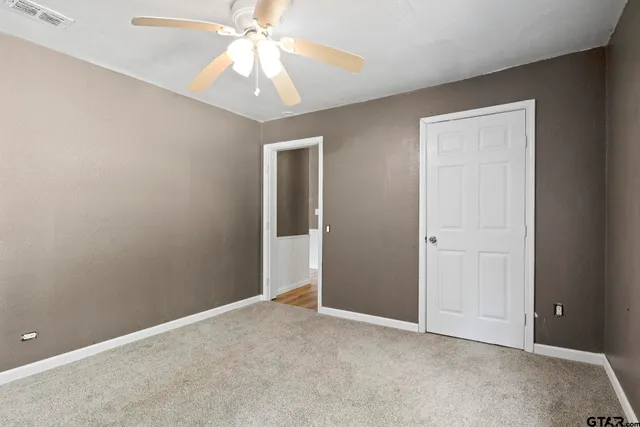 an empty room with chandelier fan and closet area