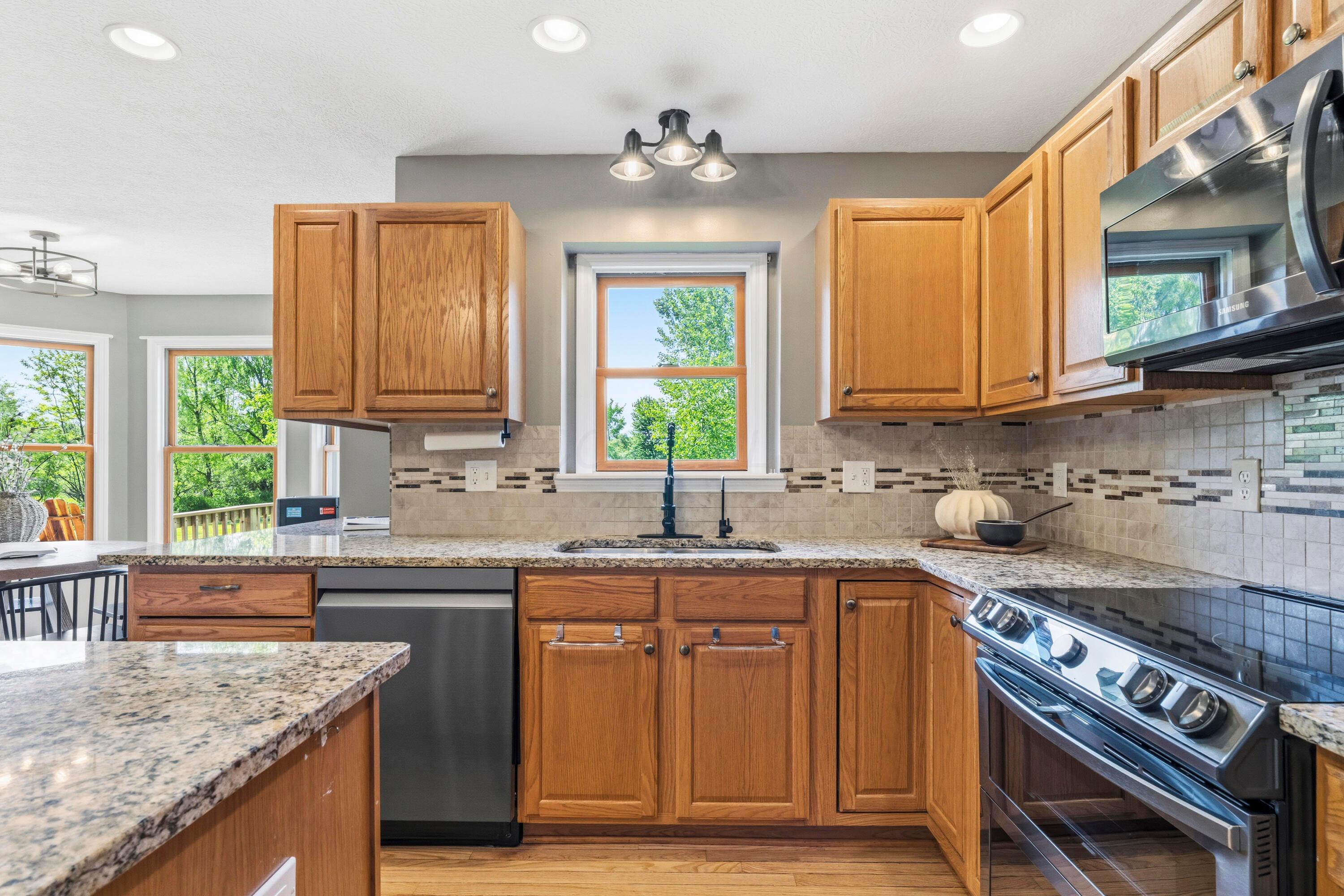8507 Benner Road Johnstown, OH 43031 - Photo 20 of 69 Large Kitchen with hardwood floors and Dining Area with bay window & double fireplace! Granite countertops, island, NEW Black Stainless Steel Appliances, including an induction oven! NEW Reverse Osmosis to sink/Fridge/Brio+