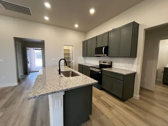 a kitchen with kitchen island granite countertop a stove top oven a sink with granite countertops and cabinets
