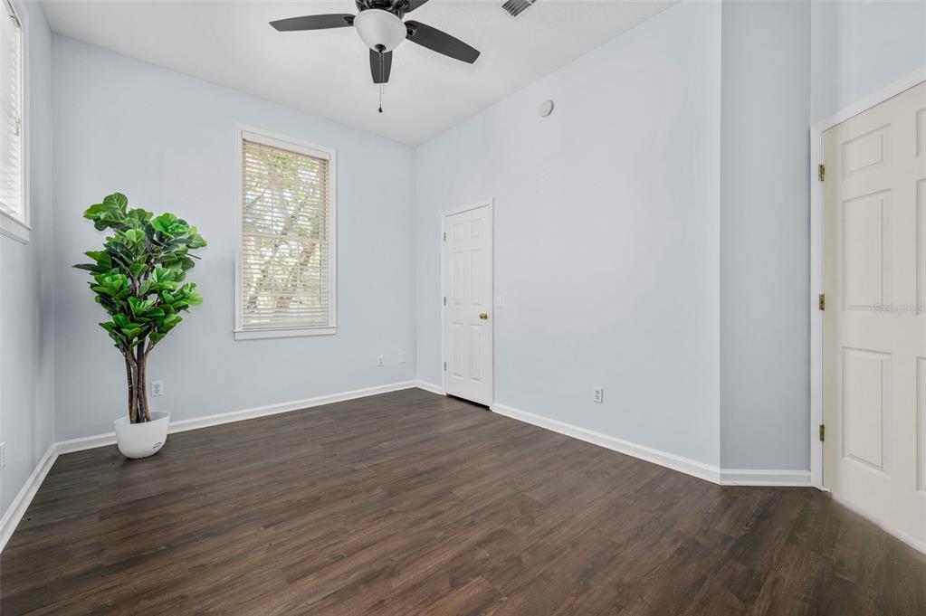 5213 Southwest 91 Terrace, Unit B Gainesville, FL 32608 - Photo 22 of 38 an empty room with wooden floor a chandelier fan and windows