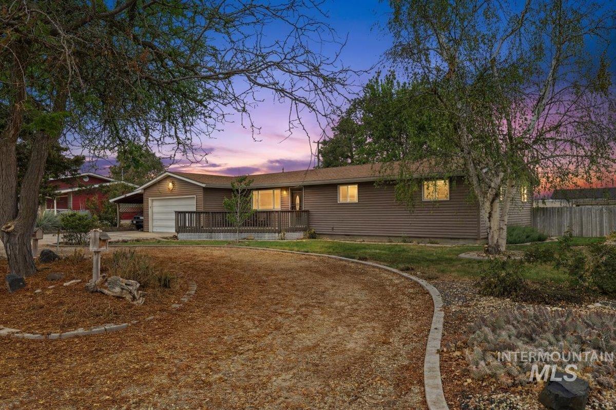 Ranch-style home with driveway, a wooden deck, and a garage