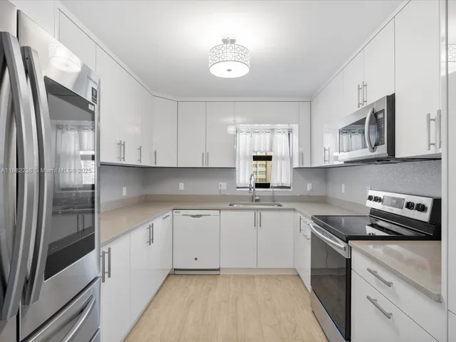 a kitchen with stainless steel appliances a sink cabinets and a refrigerator