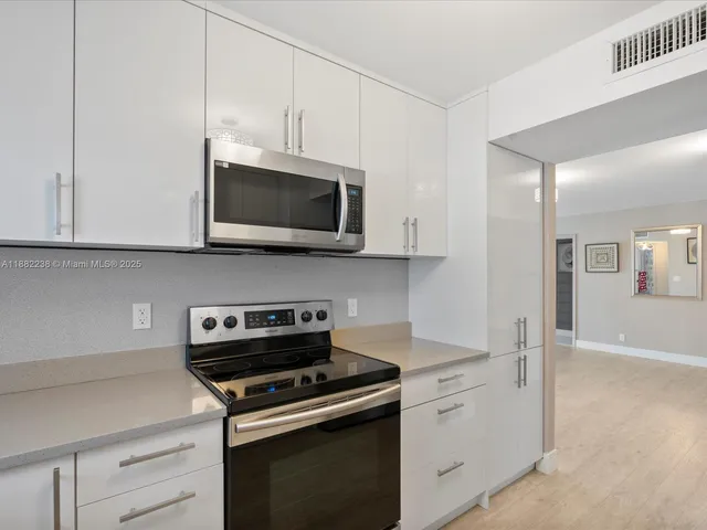 a kitchen with stainless steel appliances white cabinets and a stove top oven