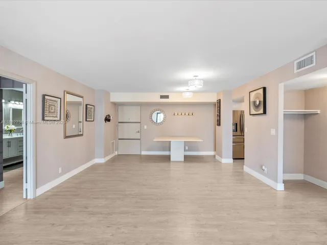 a view of a livingroom with wooden floor and kitchen view