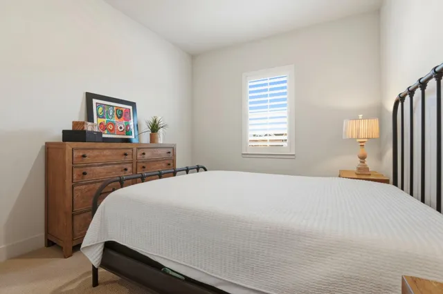 a bedroom with a bed and a dresser next to a window