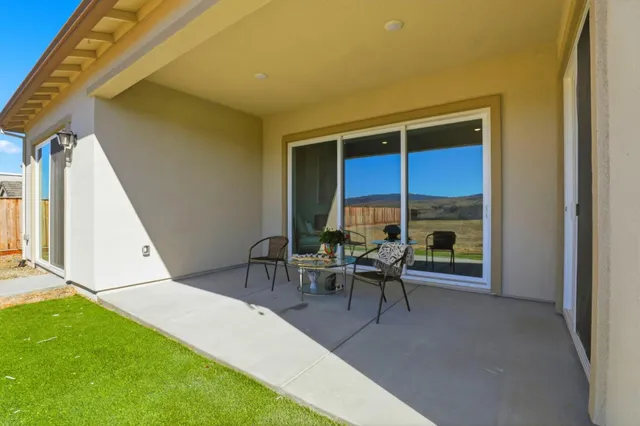 a patio with table and chairs and potted plants