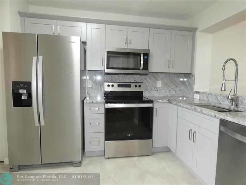 9525 Weldon Circle, Unit H110 Tamarac, FL 33321 - Photo 2 of 20 a kitchen with granite countertop white cabinets and stainless steel appliances