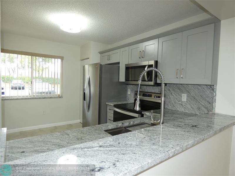 9525 Weldon Circle, Unit H110 Tamarac, FL 33321 - Photo 3 of 20 a kitchen with granite countertop a refrigerator and a sink