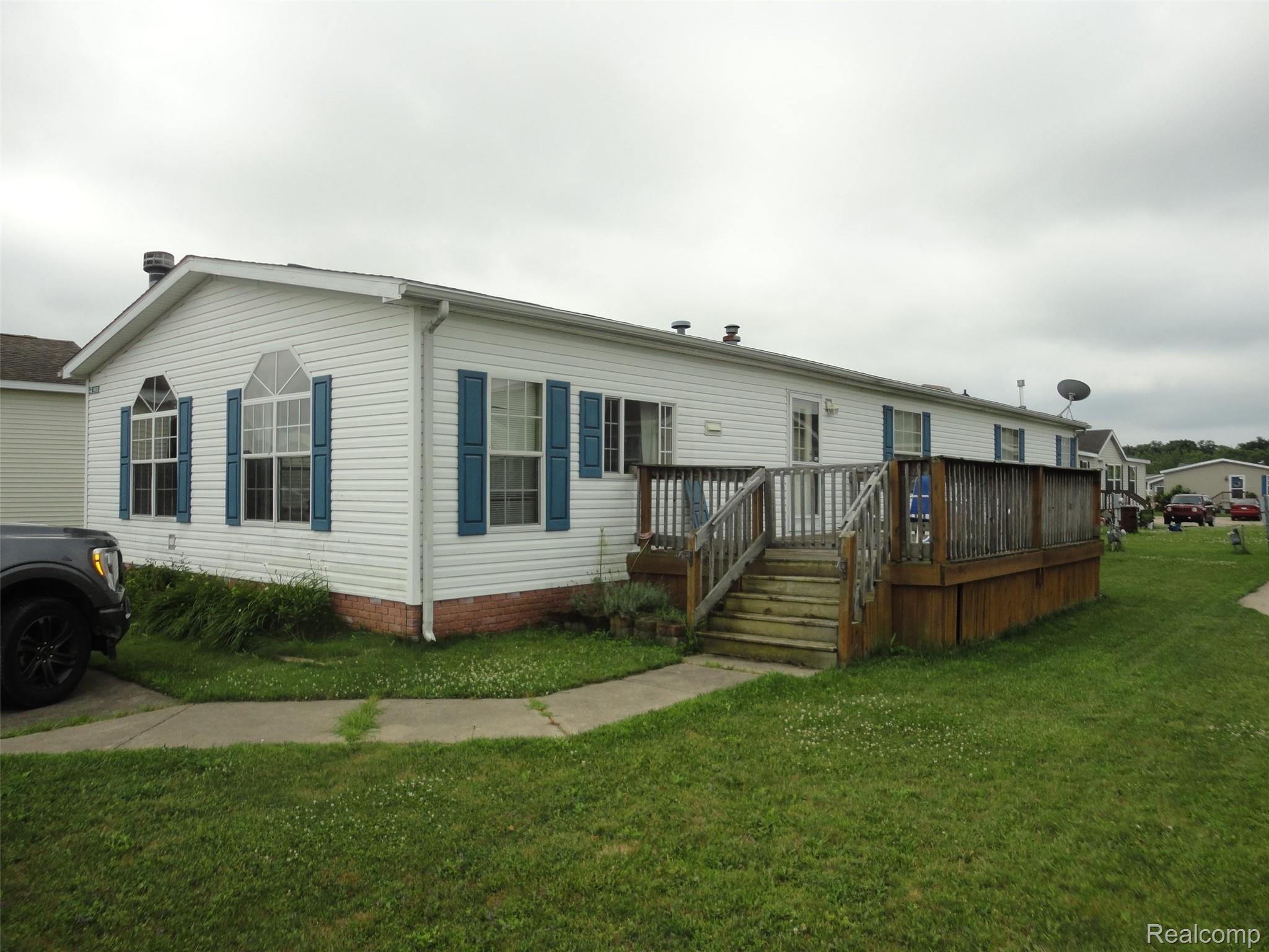 5931 Megans Ridge Monroe, MI 48161 - Photo 2 of 13 White vinyl siding exterior with blue shutters and a prominent wood deck