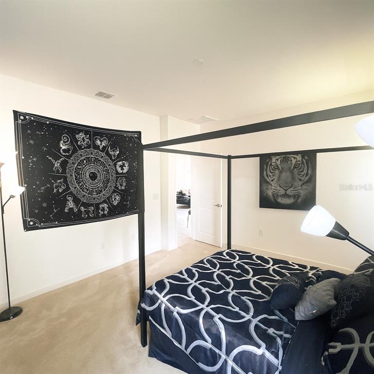 181 Trinity Ridge Circle Davenport, FL 33897 - Photo 4 of 10 a bedroom with a bed and a painting on the wall