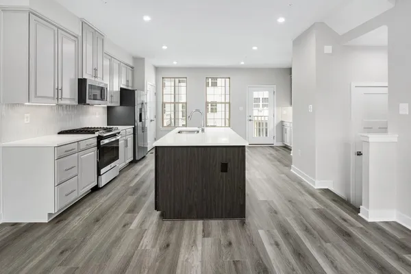 a kitchen with stainless steel appliances granite countertop a refrigerator a sink dishwasher a stove and white countertops with wooden floor