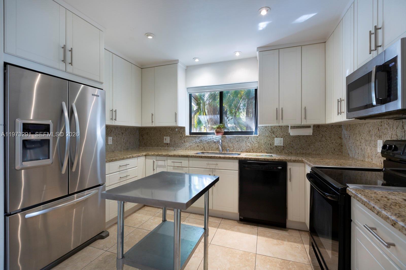 3721 Southwest 58th Avenue Miami, FL 33155 - Photo 3 of 23 a kitchen with a sink a microwave a refrigerator and cabinets