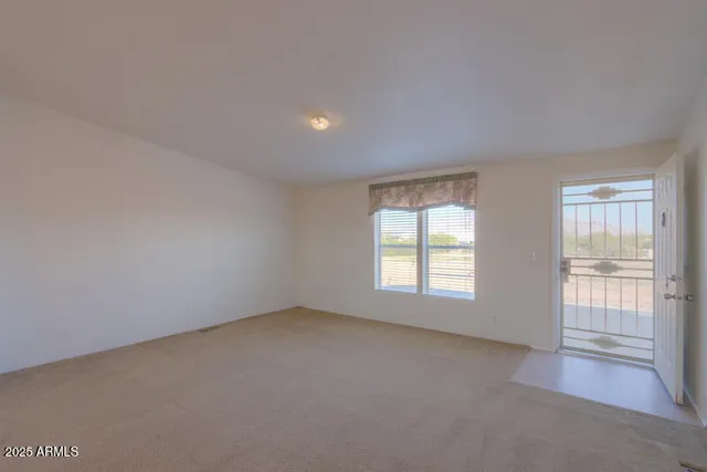 an empty room with a chandelier fan and windows
