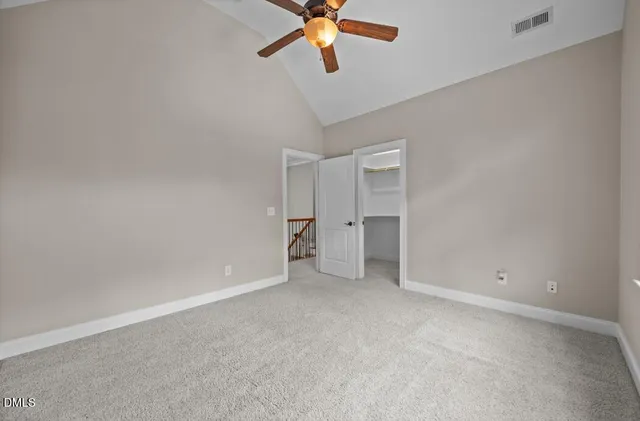 an empty room with chandelier fan and windows