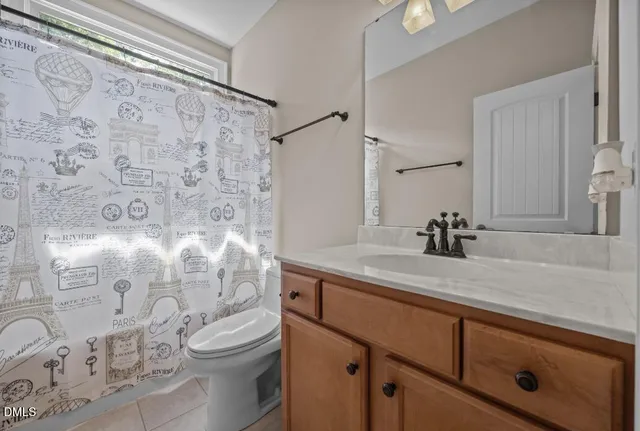 a bathroom with a granite countertop sink a toilet and a shower curtain