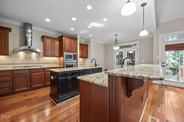 a kitchen with stainless steel appliances granite countertop a sink a stove and a wooden floors