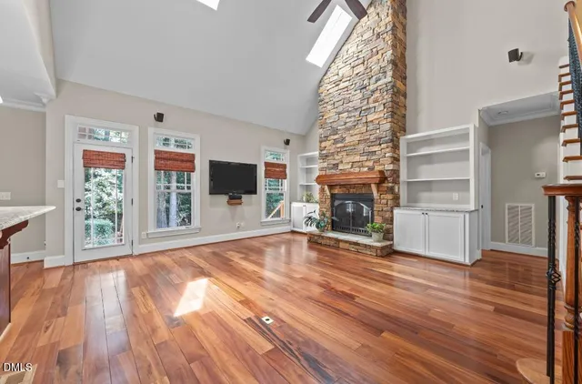 a view of a livingroom with wooden floor fireplace and windows
