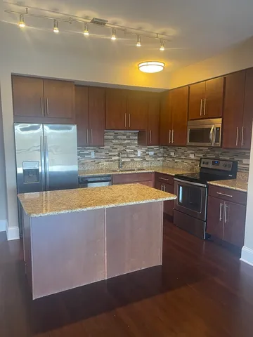 a kitchen with kitchen island granite countertop wooden cabinets a sink and a stove