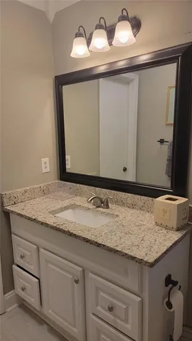 a bathroom with a granite countertop sink and a mirror
