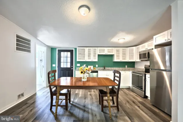a kitchen with a dining table chairs and refrigerator