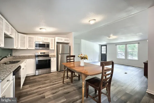 a kitchen with a table chairs a sink dishwasher a stove and a refrigerator