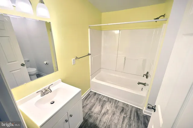a bathroom with a sink mirror and a bathtub with a shower